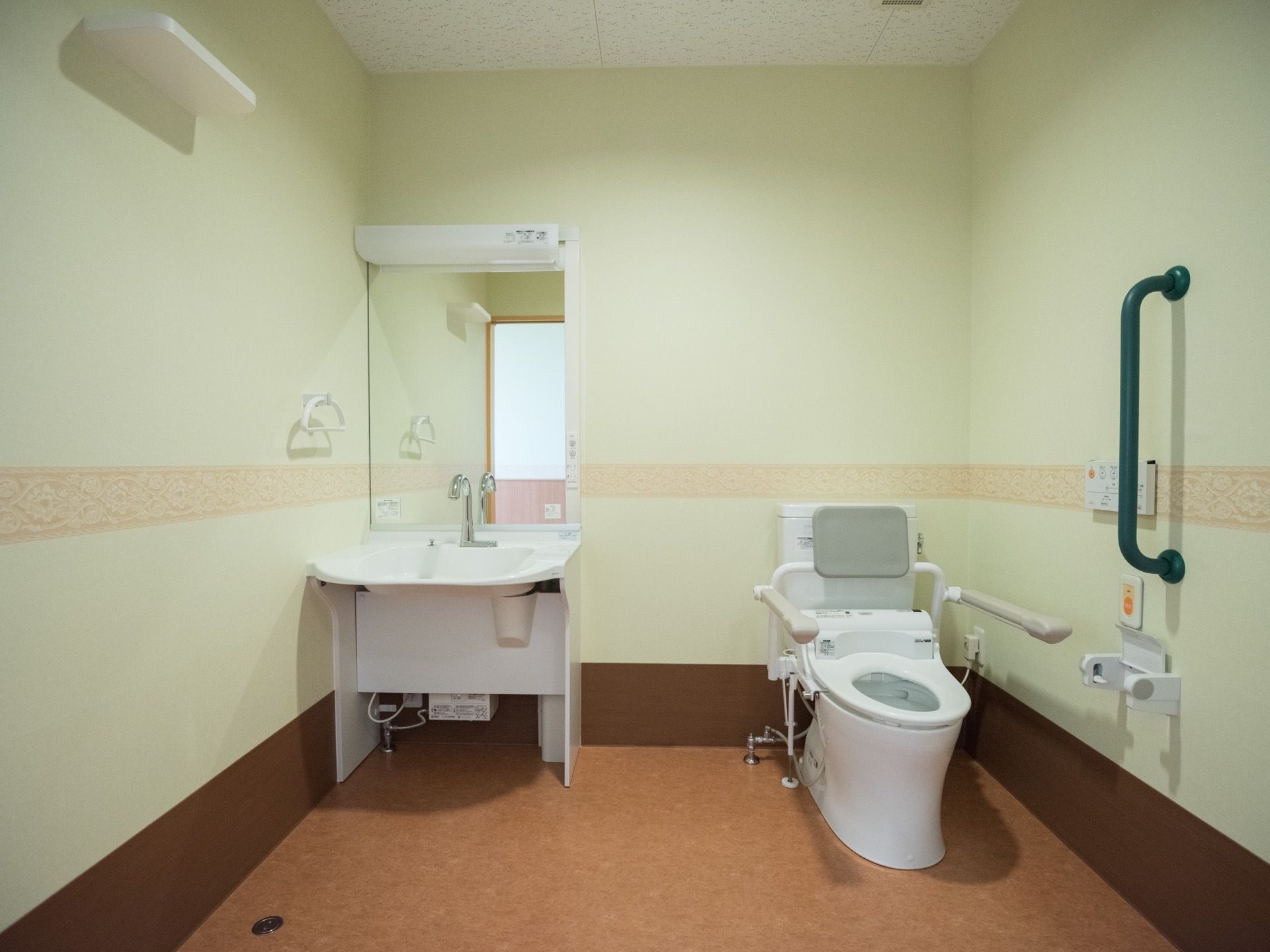 トイレと洗面台が一緒になった広い空間がある。壁や便座周りには手すりが設置され、緊急通報装置も付いている。