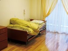 大きな窓があり明るい雰囲気。居室には布団がセットされたベッドや家具が置かれている。