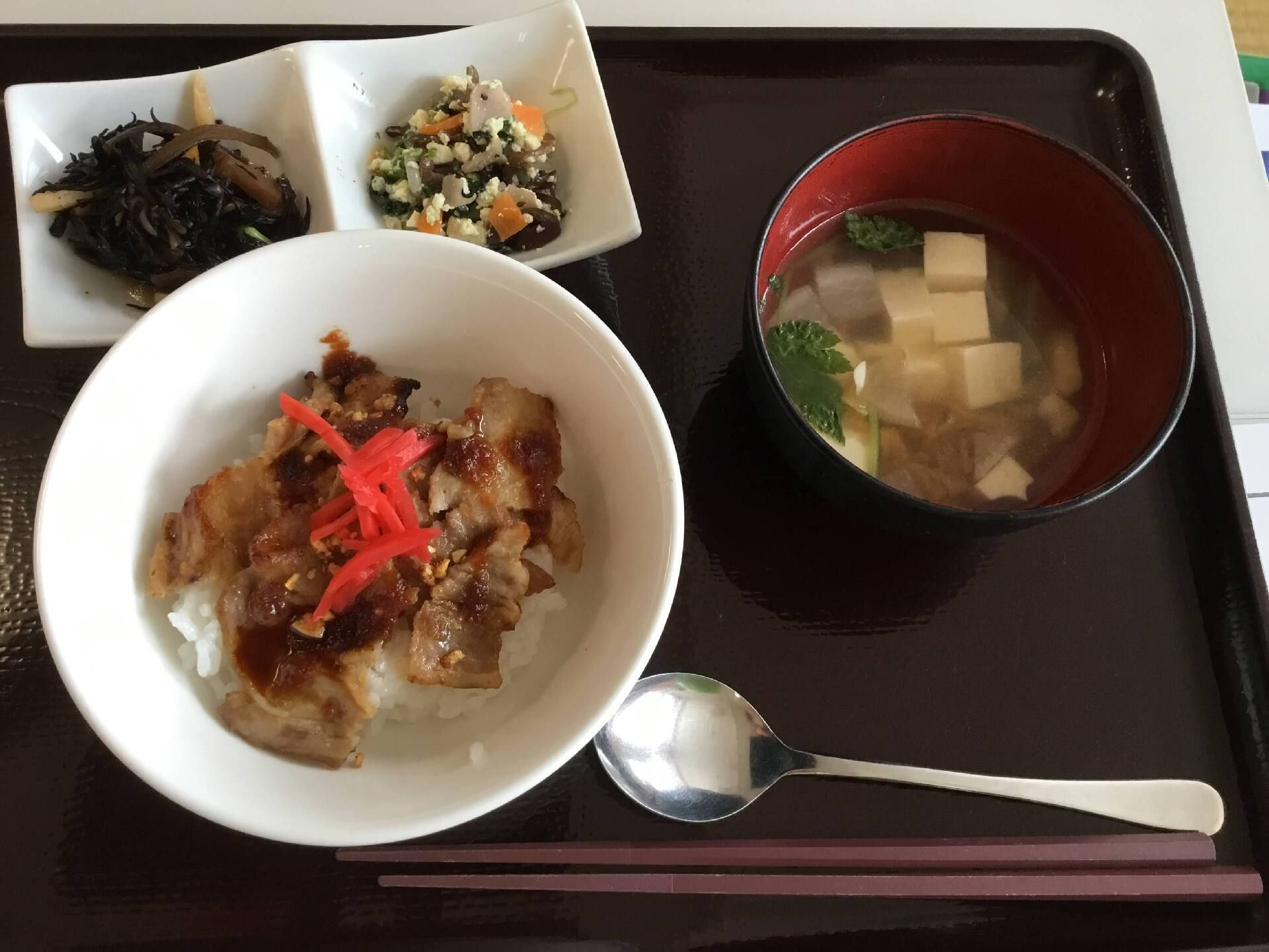 紅ショウガが乗った牛丼風のどんぶりに、ヒジキの煮物と白和え、豆腐の味噌汁が添えられている。トレーの上にはスプーンもある。