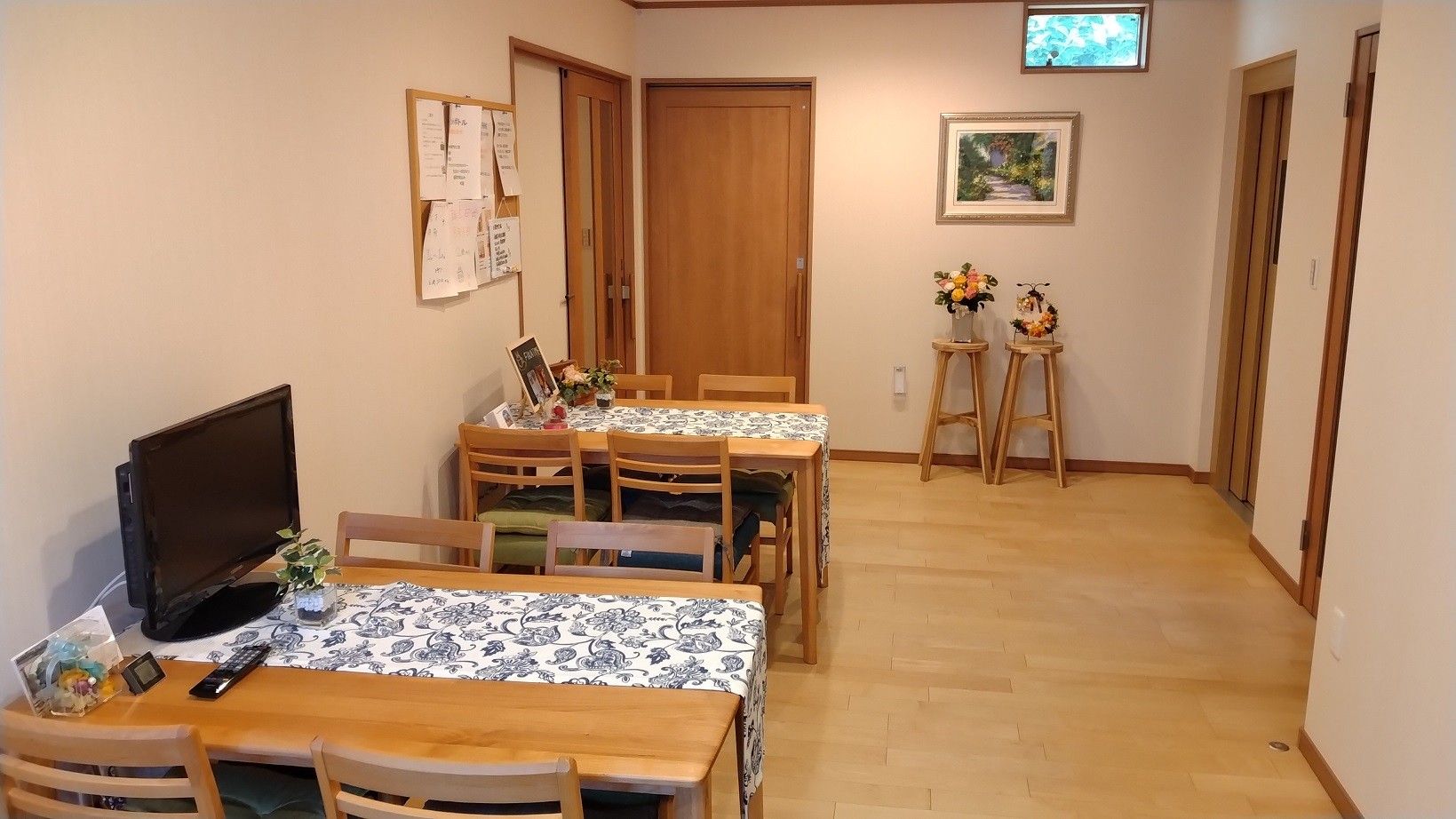 ベージュのソファを囲んで楽しそうに話している高齢女性たちの輪の中に笑顔で加わっている女性スタッフ。