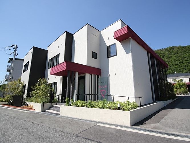 白を基調にした建物の外観写真。赤いラインがワンポイントになっている様子