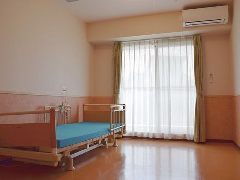 ブラウン系の建物は大きく重厚感があり、一面がガラス張りとなっている。建物の周りには草木が植えられている。