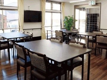 複数のダイニングテーブルが並ぶ食堂には観葉植物やテレビもある。