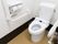 便座の横や壁に手すりの設置されたトイレがある。ペーパーホルダーの横には、紐の付いたナースコールもある。