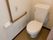 壁に木目調でＬ字型の手すりが付けられたトイレがある。手すりの近くには、ナースコールも設置されている。