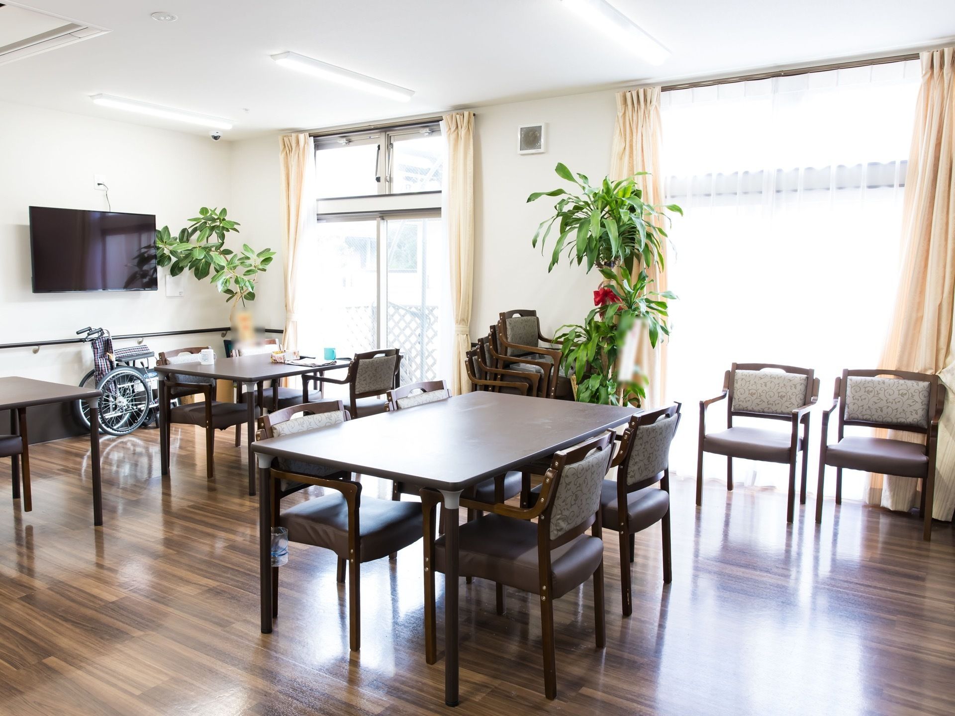 壁に大型テレビが掛けられた食堂がある。床やテーブルは木目調で統一されており、カフェのような空間になっている。