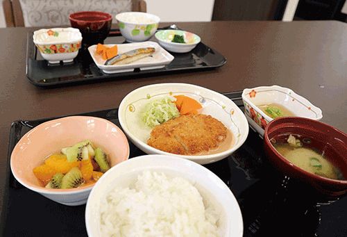フルーツのデザートが付いた、とんかつのセットと、焼き魚のセット