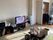 テレビやローテーブルなどが置かれた家庭的な雰囲気の部屋。奥にはフローリングの部屋がある。