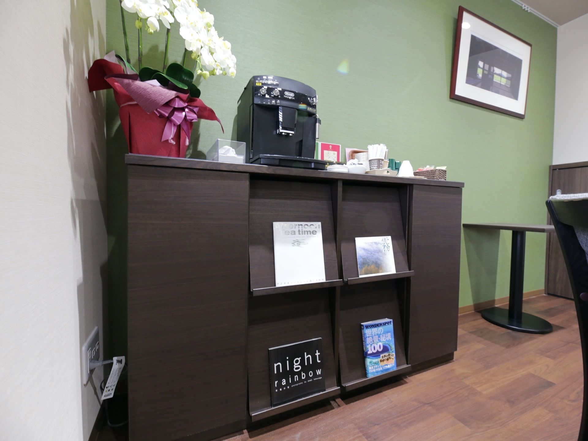 談話室奥のローチェストの上には、コーヒーメーカーをはじめ、給茶用品が備えられている。その脇には蘭が飾られている。
