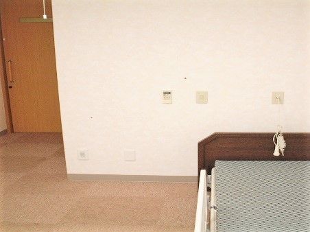 電動リクライニングベッドが設置された居室。緊急通報装置もついている。