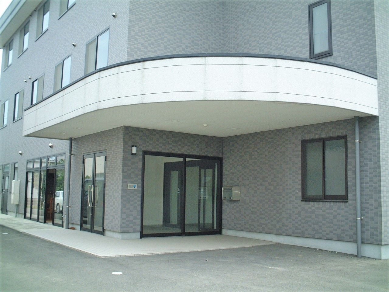 3階建ての建物はブラウンを基調とした重厚感のある造り。玄関部分には屋根が付いている。
