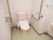 淡いピンクを基調とした、優しい雰囲気のトイレである。便器の両側の壁にはしっかり手すりが完備されている。