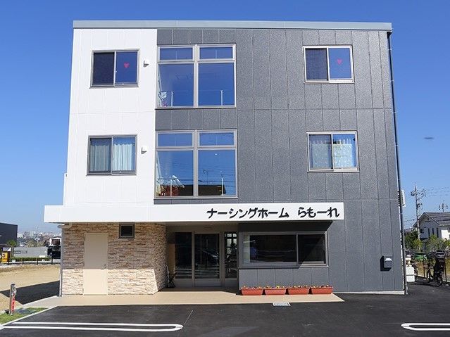 3階建ての建物はグレーと白のはっきりとした色使い。玄関には屋根もついている。