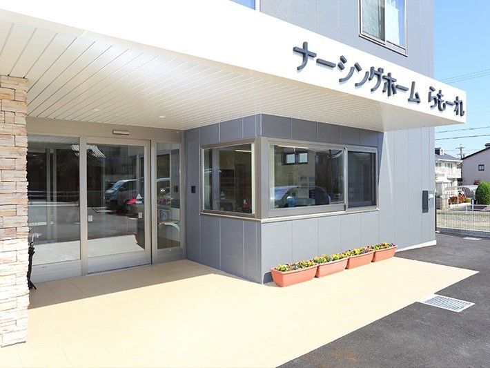 玄関周りはきれいに掃除がされていて、花が植えられたプランターが複数置かれている。
