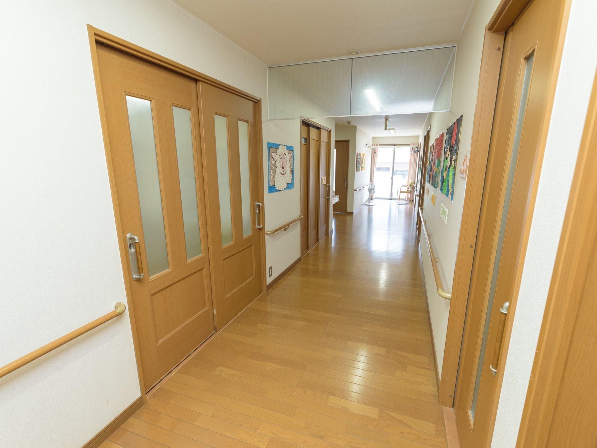 通路は、フローリングと居室のドアの色が統一されており、明るい印象となっている。羊などのさまざまな絵画が飾られている。