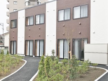 ２階建ての建物はブラウンと白でまとめられていて、大きな窓にはいずれもカーテンが付けられている。