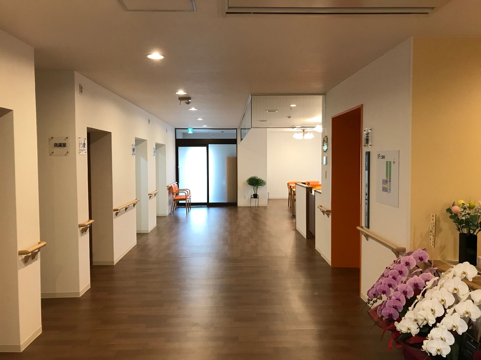 ダークブラウンの廊下は幅が広く、エレベーターの際まで手すりが設置されている。