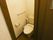 温水洗浄機能付きの洋式トイレが設置されており、上部に手洗い場が設けられている。壁にはペーパーホルダーがかかっている。