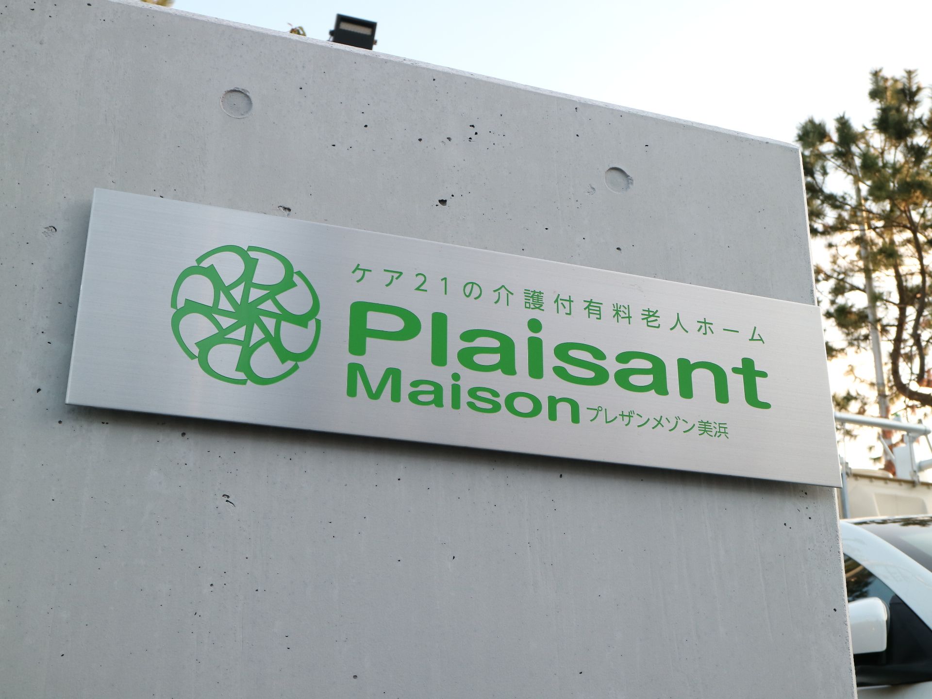 ライトグレーの門壁に設置されているアルミ素材の施設プレート