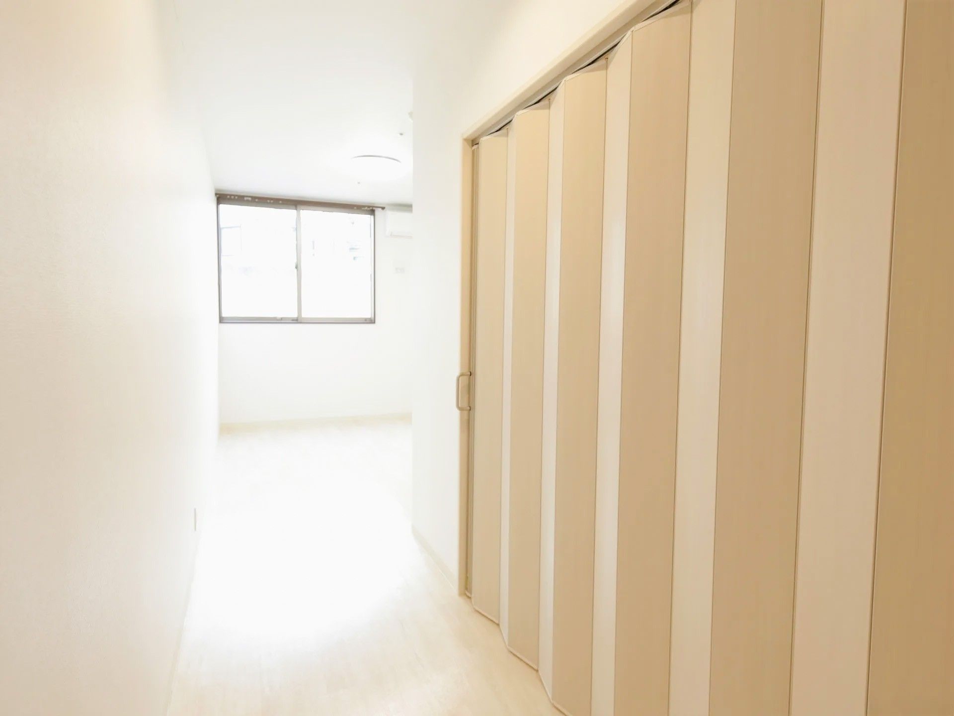 居室にあるパネルドアは、トイレスペースを区切る役割を果たしている。奥には窓があり、ベッドなどを配置できる空間が広がっている。
