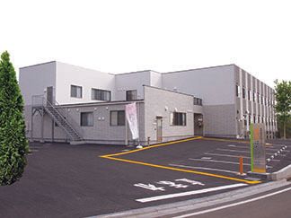 駐車場のついた鉄骨造の建物。高齢者向け施設福寿はだの戸川の外観