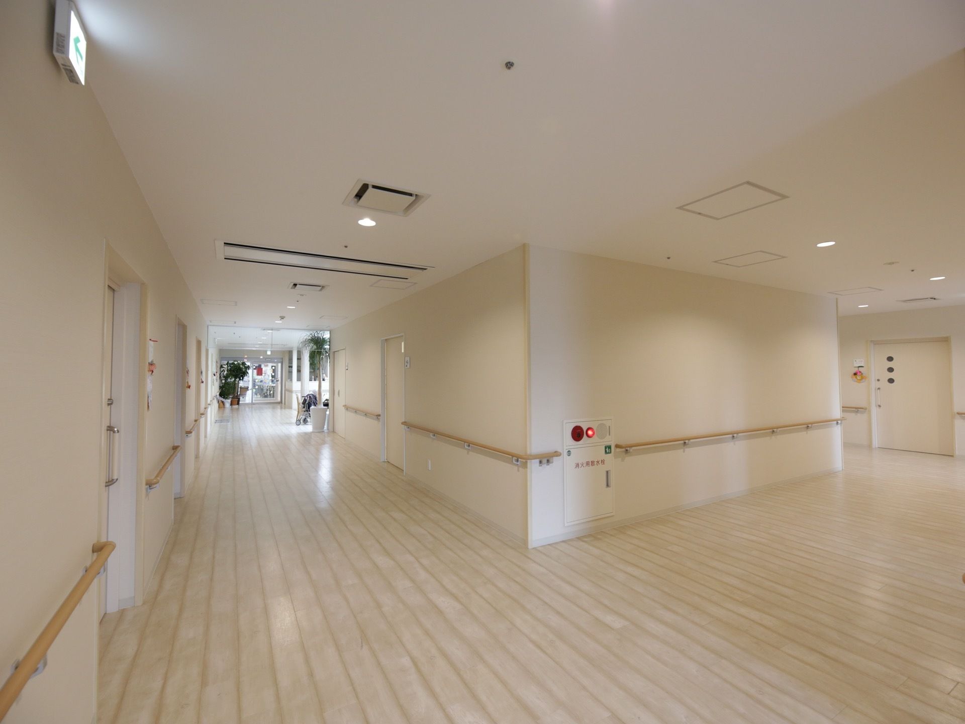 広々とした通路である。壁、床、天井が全てオフホワイトで統一されており、大変明るい。居室のスライドドアが並んでいる。