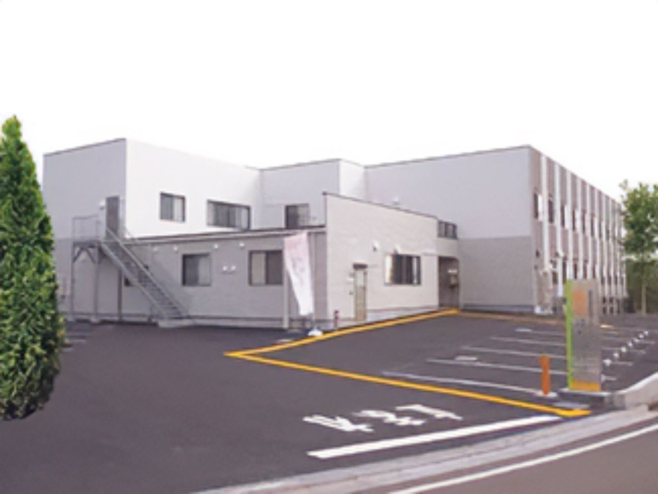 駐車場のついた鉄骨造の建物。高齢者向け施設福寿はだの戸川の外観