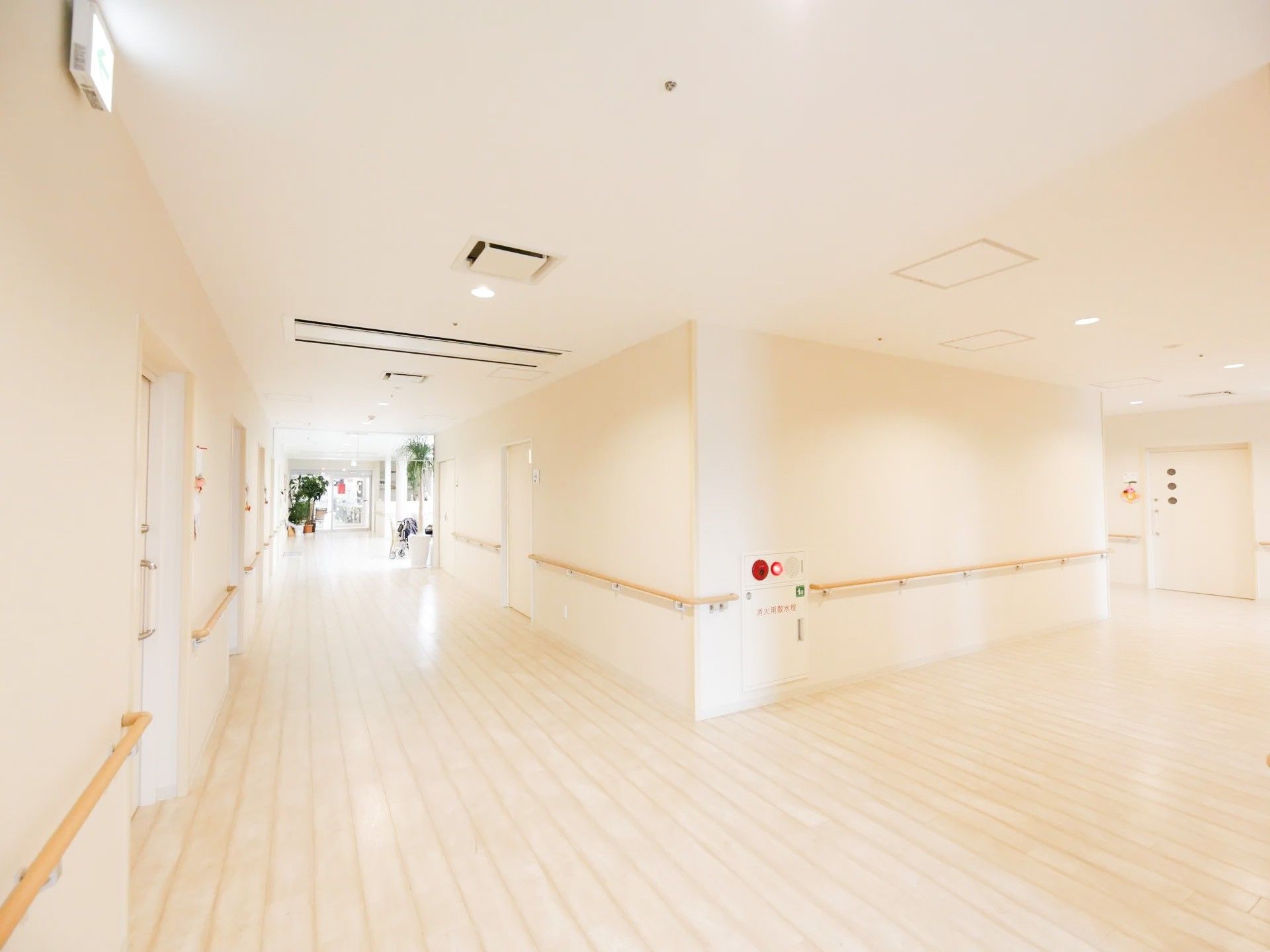 広々とした通路である。壁、床、天井が全てオフホワイトで統一されており、大変明るい。居室のスライドドアが並んでいる。