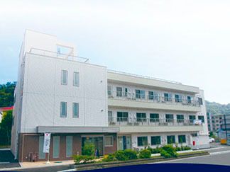鉄骨造３階建ての高齢者向け施設の外観。個室が並んでいるマンションのような建物