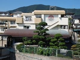 鉄骨造３階建ての建物の写真。山に囲まれた自然豊かな場所にある施設