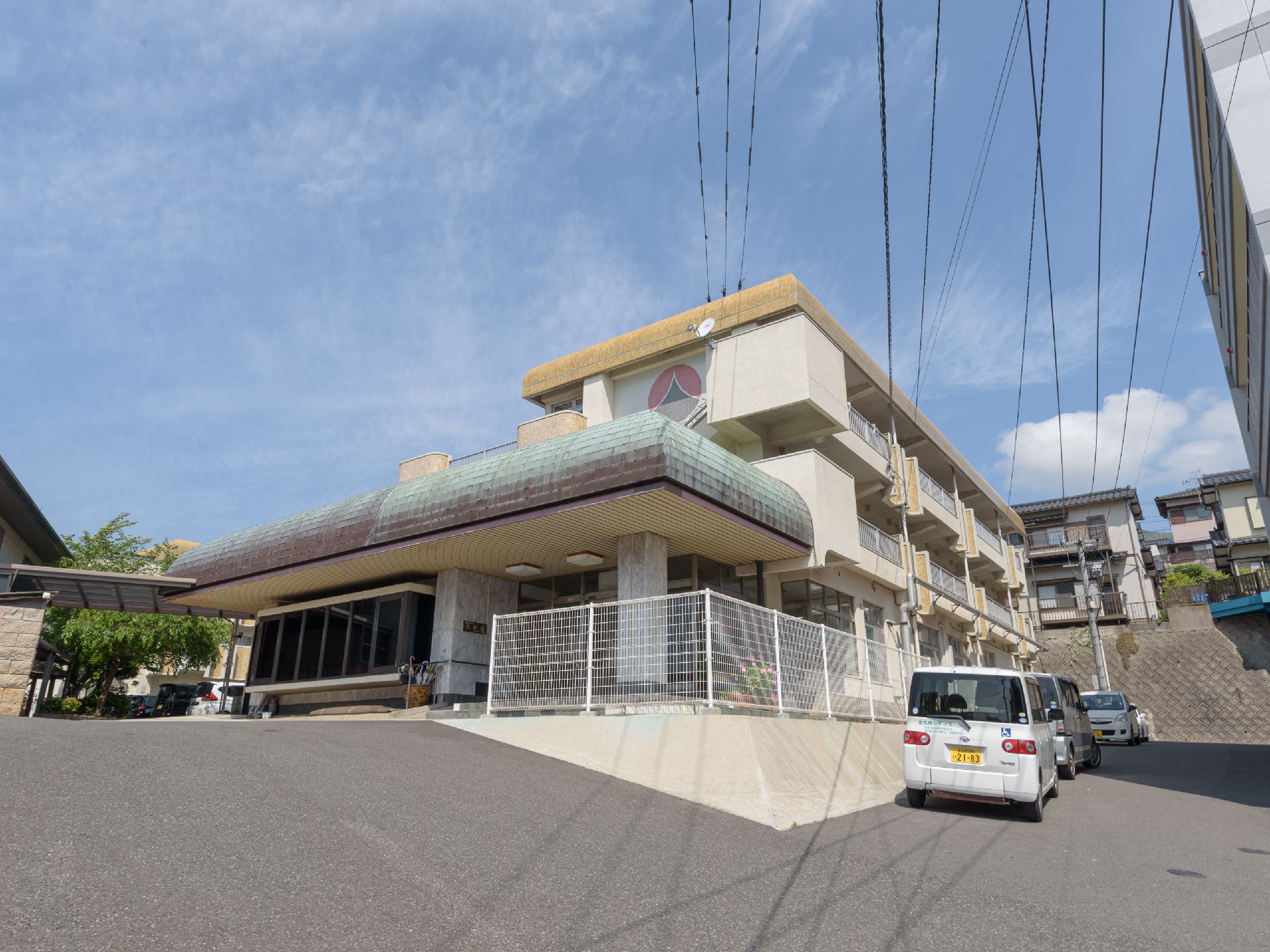 勾配の付いた高台に立地し、エントランスを完備した２階建て施設の外観