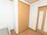 白い壁にフローリングの床の部屋に折れ戸の扉が付いたクローゼットがある。介護ベットの一部が写っている。