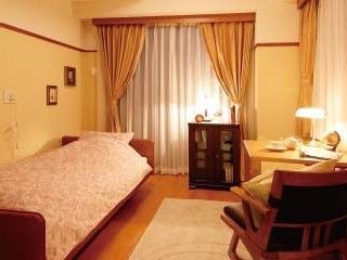 大きな窓が付いた居室にはベッドやテーブル、いすが置かれ、緊急通報装置も付いている。