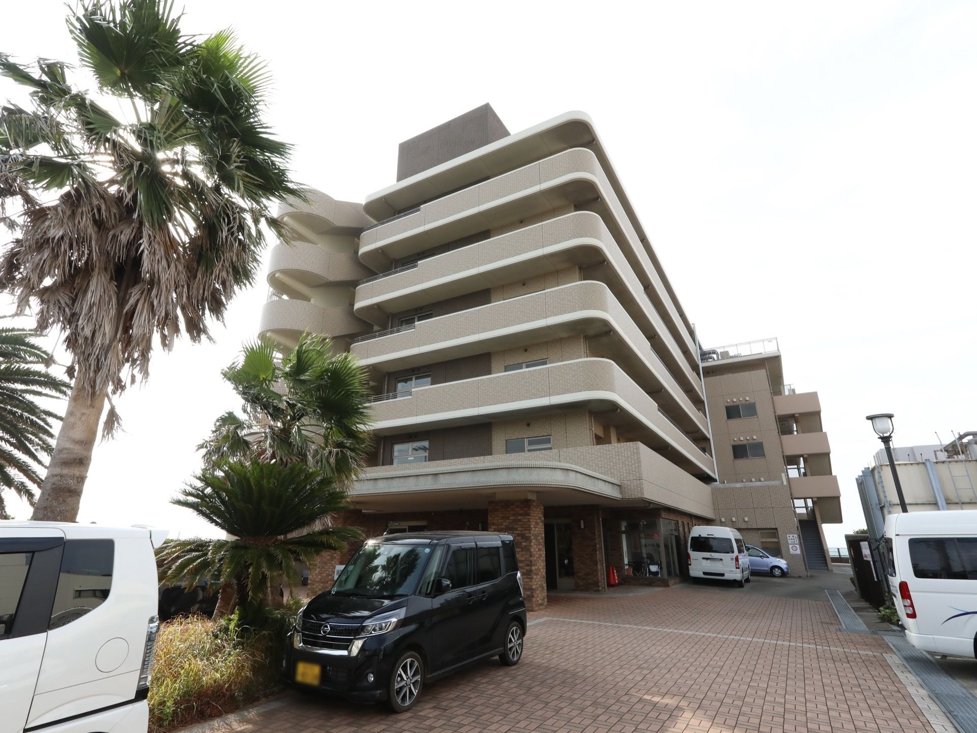 ６階建ての大きなマンションがある。敷地はタイルで舗装されていて、建物の前は駐車スペースになっている。
