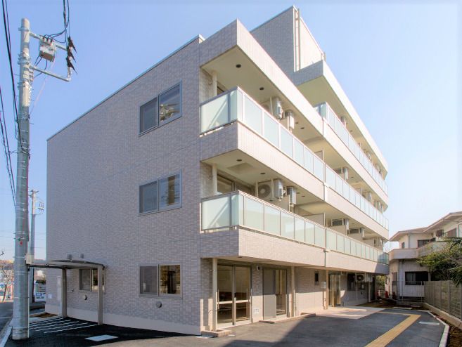 ４階建ての建物は各フロアにベランダがあり、周りに高い建物がなく日当たり良好。敷地内には点字ブロックが敷かれ、周りには住宅もある。