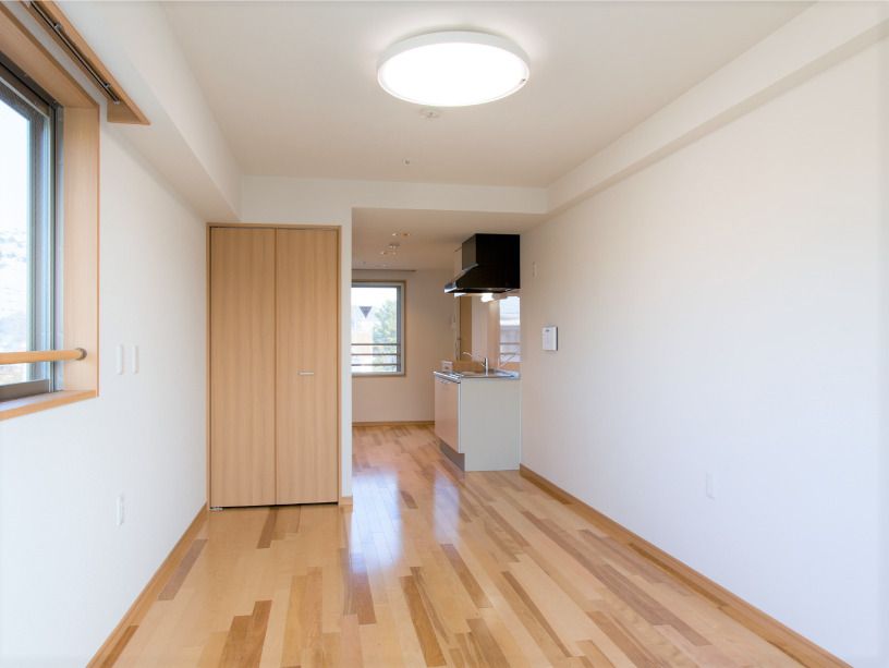 フローリングの部屋にはカーテンのない窓があり、収納付きのキッチンやクローゼットが付いていて、家具や家電はない。