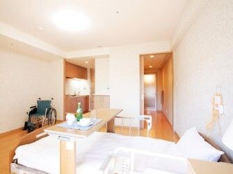 広いフローリングの部屋には車いすや寝具付きのベッドがあり、ベッドサイドには緊急通報装置がある。