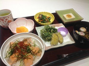 サーモンとイクラの丼に天ぷらの盛り合わせ、吸い物、野菜の和え物、ゴマ豆腐などが並んでいる。