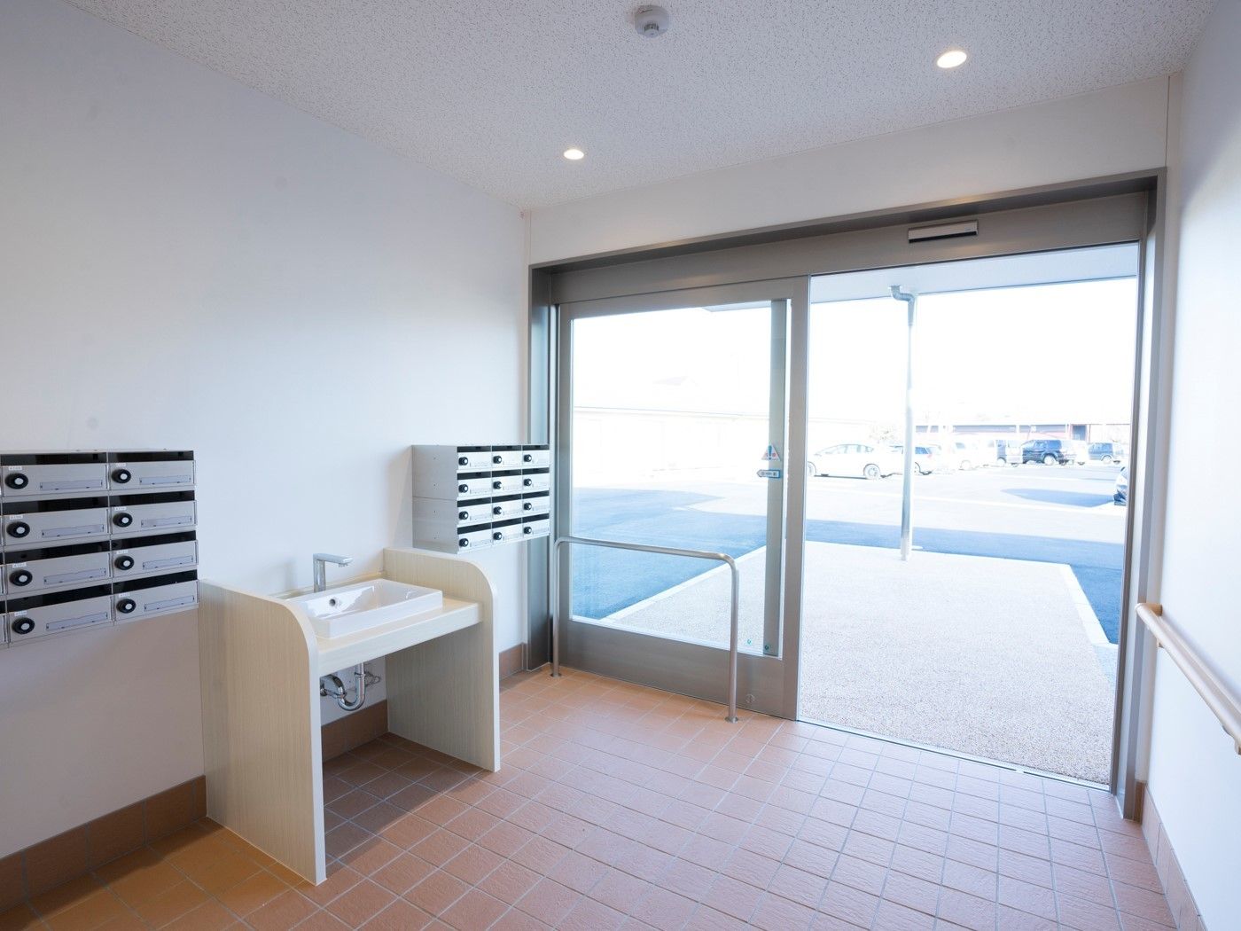 大きなドアが付いた開放感のある玄関。各入居者用の郵便受けや手洗い場がある。