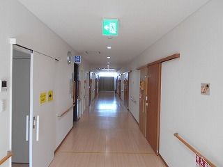 白い壁にはブラウンの手すりが付き、居室にはスライド式のドアが付いている。通路に邪魔になるものはない。