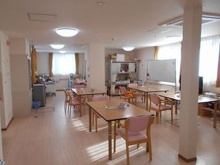 ホワイトボードが置かれた食堂には木製のダイニングテーブルが複数置かれ、大きな窓が付いている。
