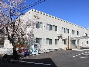 白を基調とした2階建ての建物がある敷地内には桜の木や自動販売機も置かれている。日当たりも良好。