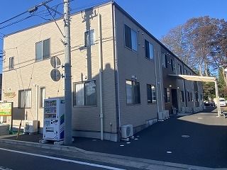 2階建ての建物の前には駐車場があり、玄関には車寄せがあり、敷地内には自動販売機も置かれている。