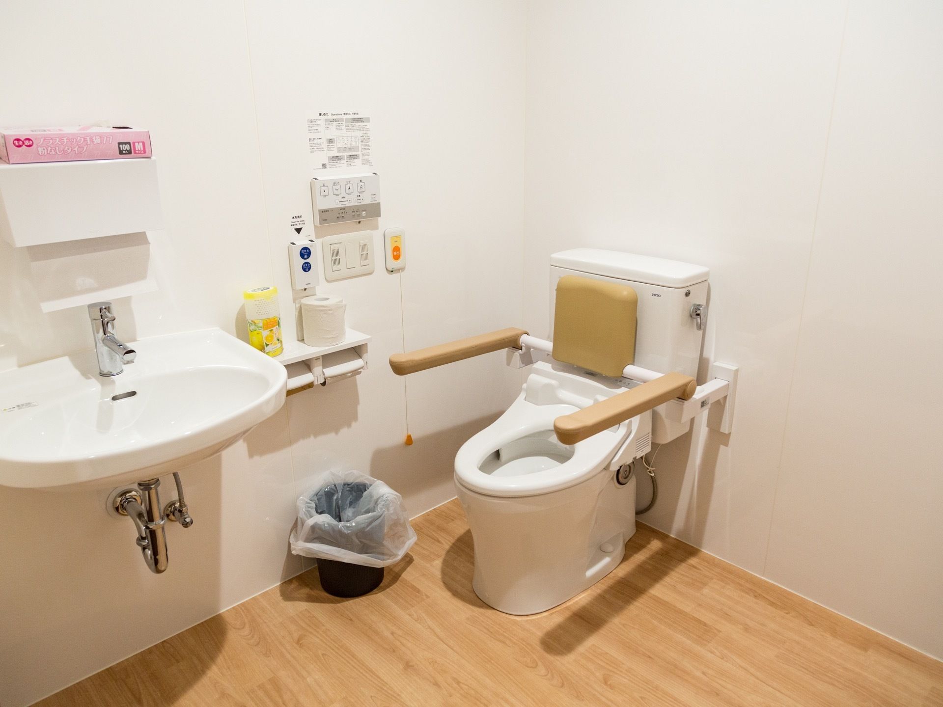 トイレの個室には、洗面台がある。便座の後ろに背もたれが、横にバーが付いている。温水洗浄式便座の操作ボタンは壁に設置してある。