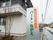 道路を通行中に見える位置に看板が出ている。緑色の文字で施設名を、そのほかをオレンジ色の枠で囲んだ文字で表している。