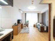 大きな窓が付いたシンプルな居室。寝具付きのベッドやいす、収納にテレビ、洗面所が付いている。