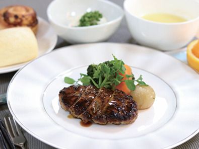 テレビやソファが設置されたリビングスペースがある食堂。木製のテーブルセットが複数置かれている。