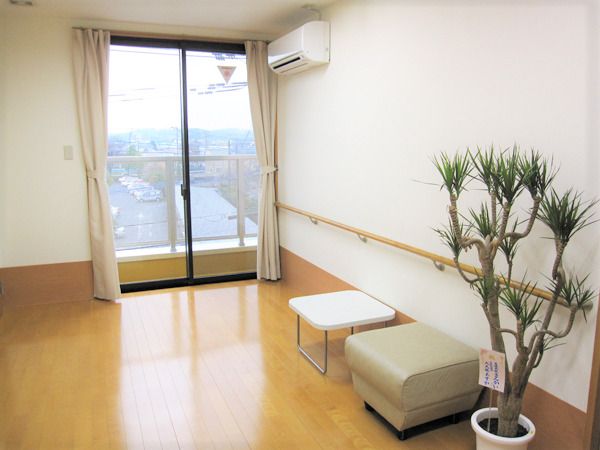 片隅に観葉植物がおいてある施設内の共有スペースの様子。エアコンがついている広めのスペース