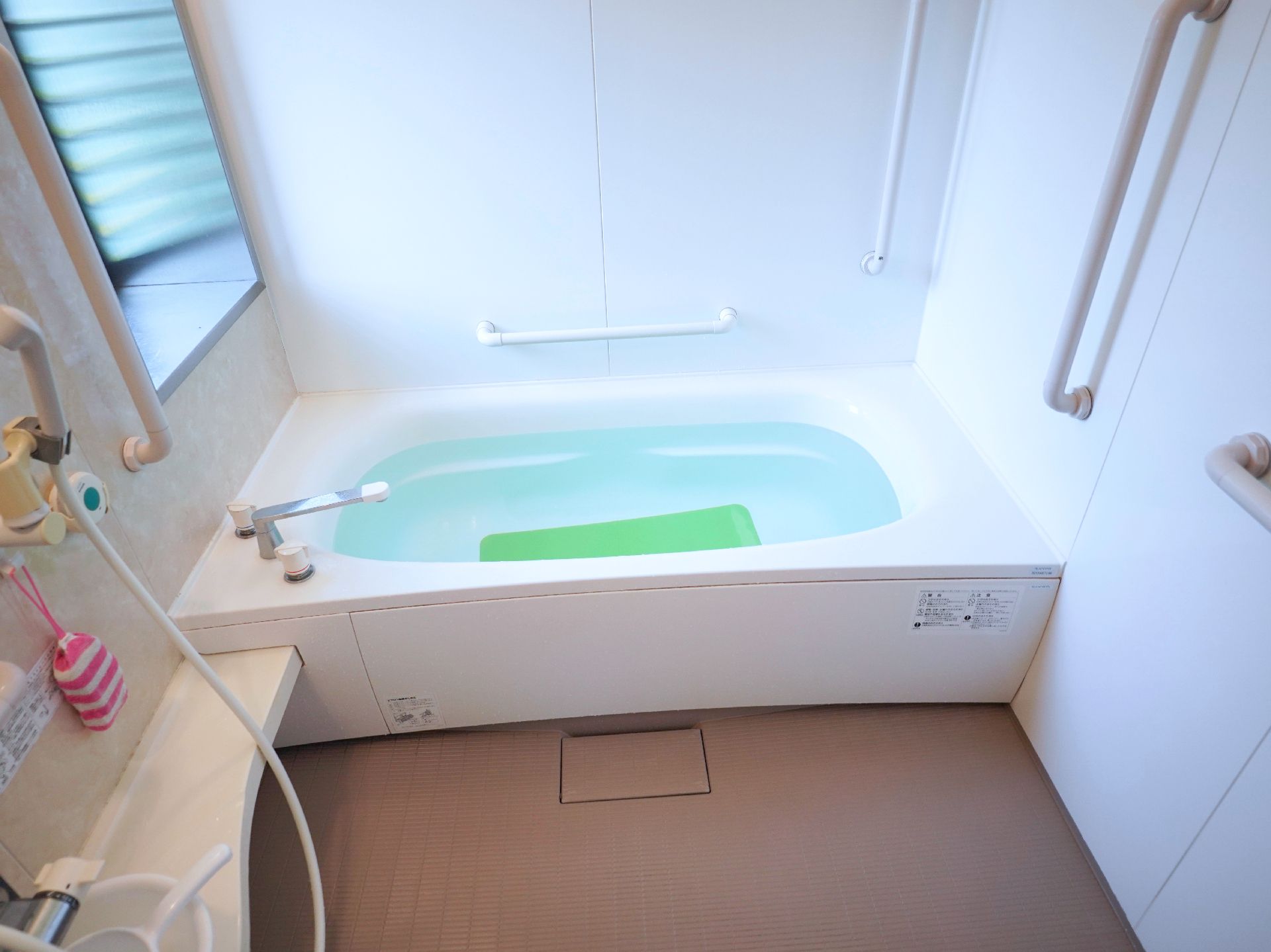 白い壁に手すりが付いた浴室