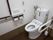トイレには温水洗浄便座が設置されている。壁には操作ボタンや緊急ボタン、トイレットペーパーホルダーなどが備えられている。
